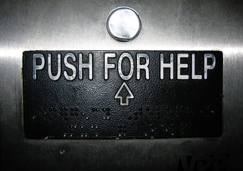 a push for help sign on a metal wall