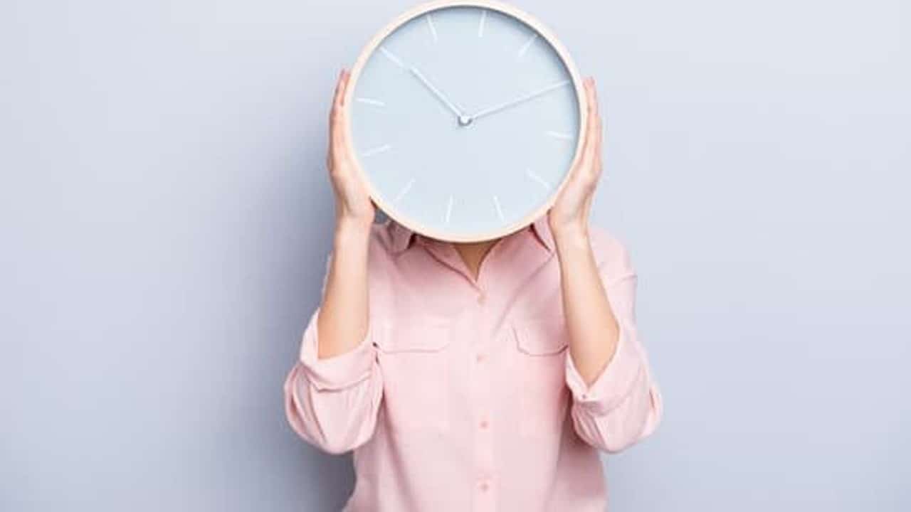 a woman covering her face with a clock