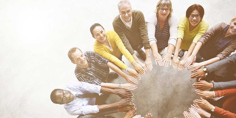 a group of people standing in a circle with their hands together