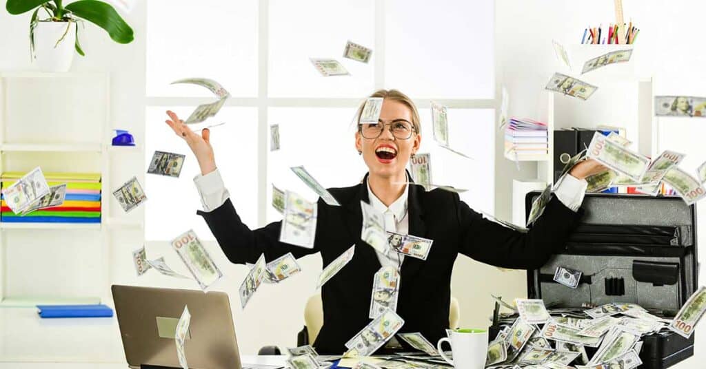 a woman sitting at a desk covered in money invest in yourself